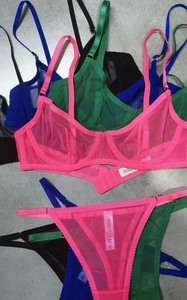 Flat lay of sheer mesh lingerie sets in pink, green, blue and black with lace detailing