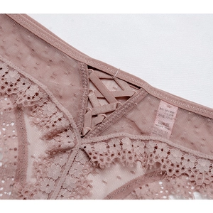 Gros plan sur un string en maille rose avec tulle à pois et bordure en dentelle cil