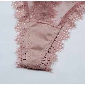 Gros plan sur la dentelle florale et le mesh transparent d'un string pour femme rose