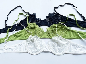 Flat lay detail showing delicate floral lace embroidery on assorted lingerie sets