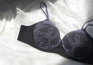 Détail du soutien-gorge noir sans armature avec dentelle violette sur soie blanche