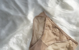 Close-up of floral embroidery on beige lace panties with premium silk background texture
