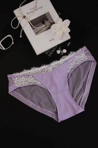 Detailed view of lavender lace panties with white floral embroidery on a dark surface