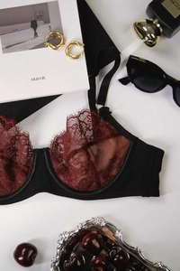 Flat lay of black and burgundy lace bra with adjustable straps and floral mesh detail