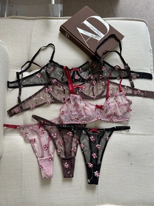 Flat lay of floral embroidered sheer lace lingerie sets in black, brown and pink