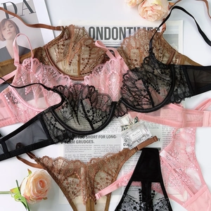 Flat lay of french lace lingerie sets in pink, black, and bronze with floral embroidery