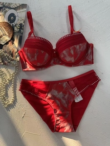Flat lay of red lingerie set with marble print, lace trim, and rhinestone accents