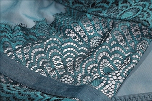 Close-up of intricate dark green lace patterns and mesh lining on a sexy bodysuit