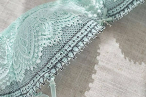 Macro shot of mint green floral lace detail with bow on a 1/2 cup push-up bra