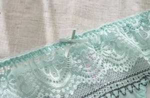 Detail of mint green lace panties with floral embroidery and delicate bow accent