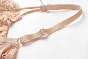 Detalle de tirantes ajustables y encaje fino en sujetador de malla beige con herrajes