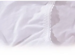 Détail de culotte blanche en soie de lait avec bordure en dentelle ondulée surpiquée