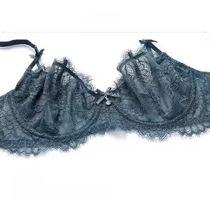 Close-up of deep teal lace bra featuring floral petal patterns and bow with metal charm