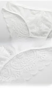 Detailed close-up of white floral lace fabric and seamless wavy edges on women's lingerie