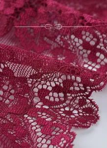 Macro detail of wine red silk fabric with intricate floral lace texture on bra cup