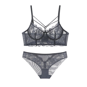 Detailed view of grey-blue lace bra with decorative cross straps and matching panties