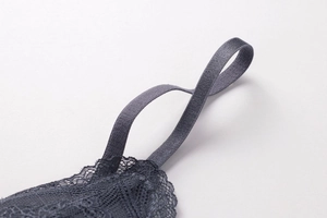 Detailed close-up of dark grey lace trim and elastic shoulder straps on a wireless bra
