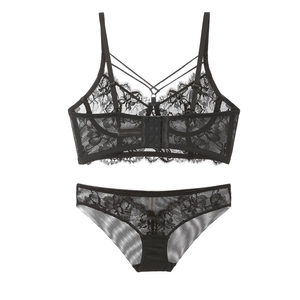 Flat lay of black lace lingerie set featuring longline bra with cross straps and floral details