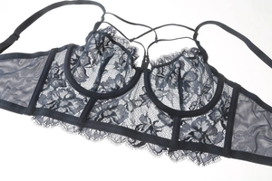 Detailed view of black floral lace bra with cross strap design and mesh side wings