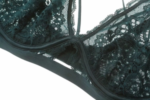 Détail macro de dentelle florale vert foncé et bordure en satin d'un soutien-gorge