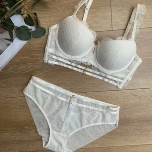 Ensemble de lingerie en dentelle blanche avec anneaux dorés sur sol en bois