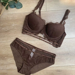 Détail à plat d'un ensemble soutien-gorge en dentelle marron foncé avec anneaux en métal