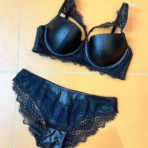 Detailed view of black lace and faux leather lingerie set laid flat on surface