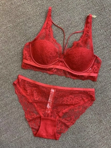 Detailed close-up of red floral lace bra and matching panties on a textured surface