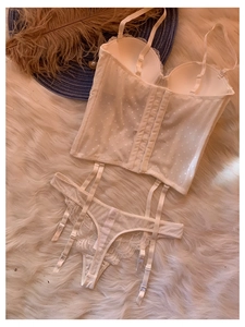 Ensemble lingerie corset en dentelle blanche avec porte-jarretelles sur tapis en fausse fourrure
