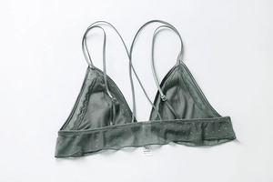 Detail of dark grey triangle cup lace bra with mesh dots and thin straps on white background