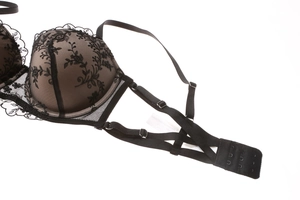 Detail of floral embroidery on black lace bra with adjustable straps and multi-row hooks