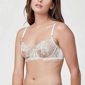 Dettaglio ravvicinato del reggiseno in pizzo francese bianco con motivi floreali