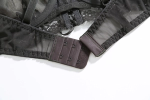 Detail of black lace bra back closure with three-row hook-and-eye design on mesh fabric