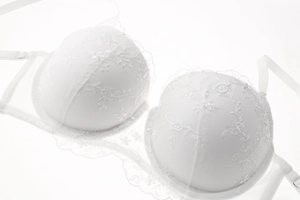 Detail showing white lace embroidery texture and wavy trim on push-up bra cups