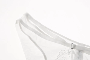 Macro detail of white floral embroidery on sheer lace mesh fabric with silver metal clasp