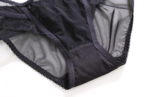 Detailed view of women's black satin underwear featuring sheer mesh and wavy lace edges