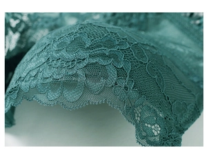 Detailed close-up of dark green floral lace fabric with delicate scalloped edge