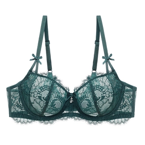 Detail of dark green lace bra with floral patterns, bow accent and silver flower charm
