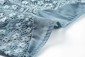 Gros plan sur la dentelle française bleue avec motifs floraux et coutures en zigzag