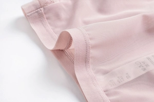 Close-up of pink breathable mesh lace fabric with neat double-needle stitching detail