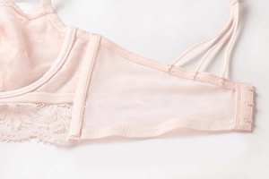 Détail de broderie en dentelle florale et fermeture à trois agrafes sur soutien-gorge rose