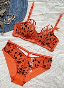 Dettaglio del set intimo arancione in rete con ricamo floreale nero e spalline