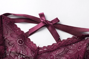 Détail de sous-vêtement en dentelle florale rouge vin avec nœud en satin et bretelles