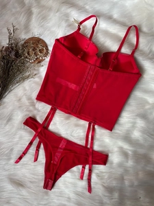Detailed view of red lace corset lingerie set with satin finish on plush rug