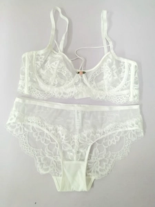 Détail d'un ensemble de lingerie en dentelle blanche avec broderies et rose rose