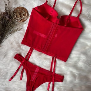 Red faux leather corset bra set with garter belts and lace details on white faux fur