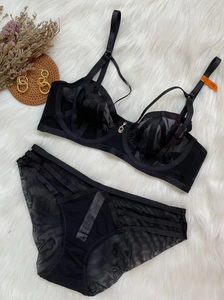Detailed flat lay of a black lace lingerie set with mesh fabric on white plush rug