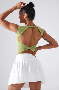 Détail des bretelles croisées sur le haut de yoga vert clair et jupe plissée blanche