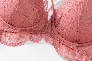 Détail du soutien-gorge en dentelle rose poudré avec motifs floraux et bordures festonnées