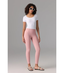 Haut court de yoga blanc ajusté et legging rose taille haute portés par un modèle
